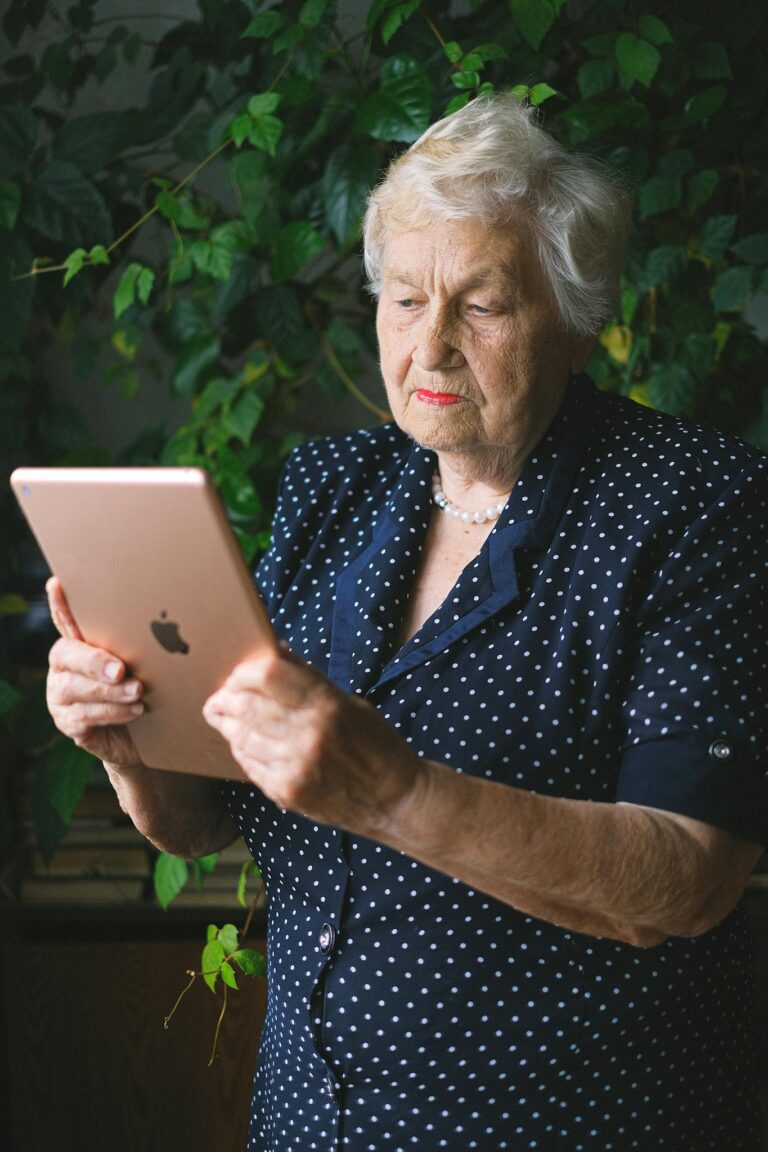 Elderly woman browsing modern tablet in garden